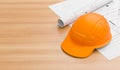 Orange or brown safety helmet on wooden table with blueprints. Safety helmet for welders and workers with high heat application. Royalty Free Stock Photo