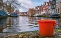 Orange Bucket on Canal Bank with Dutch Architecture and Moored Boats