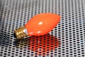 Orange bulb on a perforated steel plate