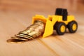 Mini bulldozer truck loading stack coin with pile of gold coin. Royalty Free Stock Photo