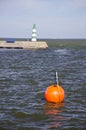 Orange buoy and lighthouse in sea dock Royalty Free Stock Photo