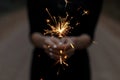 Orange burning sparklers in hands of a young woman in a black t-shirt outdoors. Girl is holding a festive Bengal fire. Royalty Free Stock Photo