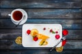 Orange cake with a cup of tea fresh raspberries on a white plate with rose petals. Top view. Beautiful wooden background Royalty Free Stock Photo