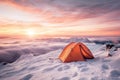orange camping tent stands on a snowy high mountain at sunrise or sunset