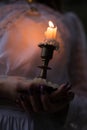 Orange candle in a candlestick and hold her hands Royalty Free Stock Photo