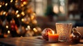 Orange Candle with some red Christmas balls put on a wood table with a blurry luminous Christmas tree