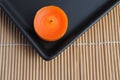 Orange candls in black dish on bamboo background Royalty Free Stock Photo