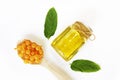 Orange capsules in a spoon and aromatic yellow oil in a jar