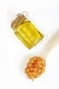 Orange capsules in a spoon and aromatic yellow oil in a jar