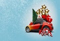 Orange car on blue background. Its snowing. Christmas tree, present boxes, balloons, snow globe nearby. Collage. Copy Royalty Free Stock Photo