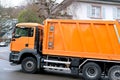 Orange cargo garbage truck driving through LUCERNE city streets, SWITZERLAND, collecting garbage from bins, waste recycling