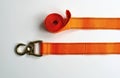 Orange cargo strap with metal hook and carabiner clip. Webbing tie down system with coiled strap secured for transport. Load Royalty Free Stock Photo