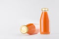 Orange carrot vegetables juices in glass bottles with gold empty cap for label mock up on white background with copy space. Royalty Free Stock Photo