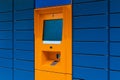 Orange cashpoint minibank with blank copyspace screen on blue panel tile background diagonal view