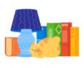 Orange cat sleeping beside colorful books under blue lamp. Cozy home reading corner with sleeping pet. Books and reading Royalty Free Stock Photo