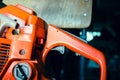 Orange chainsaw close-up. Gasoline tool controls, off button and gas pedal. Filler neck of the tank for the fuel mixture Royalty Free Stock Photo