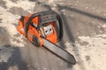 Orange chainsaw stands in sawdusts