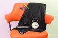 On the orange chair is a set of objects for creating a hairstyle and a black alarm clock Royalty Free Stock Photo