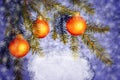 Orange Christmas ornaments on spruce branches on a blue shiny background with snowflakes. Place for the text. Blank for Royalty Free Stock Photo