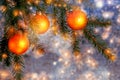 Orange Christmas ornaments on spruce branches on a shiny blue-silver background. New Year`s or Christmas background Royalty Free Stock Photo