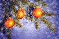 Orange Christmas ornaments on spruce branches on a shiny blue-silver background. New Year`s or Christmas background Royalty Free Stock Photo