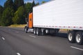 Orange classic semi truck and trailer on highway Royalty Free Stock Photo