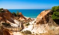 Orange cliffs, blue sea, footbridge, beach in `Falesia` in Algarve, Portugal