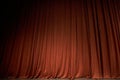 Orange closed curtain or drapes in theater with copy space. Theatrical performance concept. Spot of light on the curtain