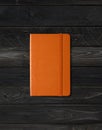 Orange closed notebook on black wood background