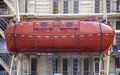 An orange closed-type Arctic lifeboat on board an icebreaker