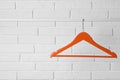 Orange clothes hanger on rail near white brick wall. Space for text Royalty Free Stock Photo