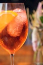 Orange cocktail with orange garnish in wine glass, aperol spritz in sunny setting