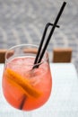 Orange cocktail with ice and two straws. Aperol spritz cocktail on table. Drinks in outdoor bar. Summer party background. Royalty Free Stock Photo