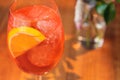 Orange cocktail with orange garnish in wine glass, aperol spritz in sunny setting