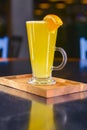 Orange cocktail with orange slice on top. Served in a tall glass over blurred restaurant background. Selective focus Royalty Free Stock Photo