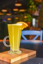Orange cocktail with orange slice on top. Served in a tall glass over blurred restaurant background. Selective focus Royalty Free Stock Photo