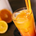 Orange coctail with yellow straw on wooden table Royalty Free Stock Photo