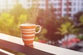 Orange coffee cup on balcony of hotel and blurred view of building Royalty Free Stock Photo