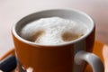 Orange coffee cup with cappuccino and milk foam Royalty Free Stock Photo