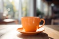 Orange coffee cup, quietly placed on a tabletop