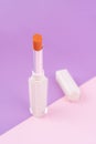 A orange color beautiful lipsticks on pink and purple background