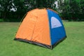 Orange color family camping tent with ground sheet setup on green park campsite