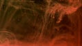 Orange color paint ink diffuses in water in slow motion on black background with inky cloud swirling and abstract smoke