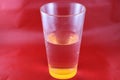 Orange Colored Bottom Of Drinking Glass Creates Optical Illusion, With Red Background