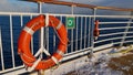 Orange colored life belt with the ship's name mounted at railing of upper deck of Hurtigruten cruise ship. Royalty Free Stock Photo