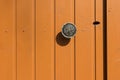 An orange-colored wooden door with a metal handle and a keyhole Royalty Free Stock Photo