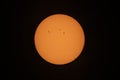 The orange coloured afternoon sun glowing with many sunspots using a homemade solar filter against a black background. Royalty Free Stock Photo