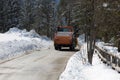 Orange-coloured Snowplough Operating on the Road with Snow on the Edges