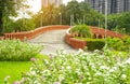 Orange concrete arch curve brige and lake in a beautiful garden, fresh pink and white West Indian perwinkle petals