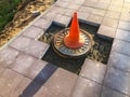 Orange cone triangular shape mounted on asphalt. the cone rests on a hole without bricks. construction of a new area, destruction